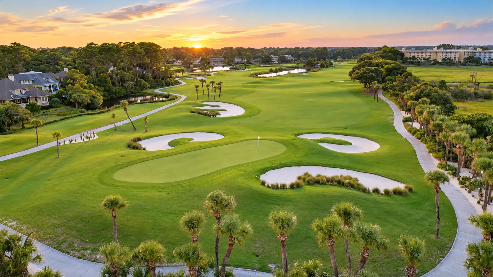 Full golf course with lagoons at sunset, shot by drone