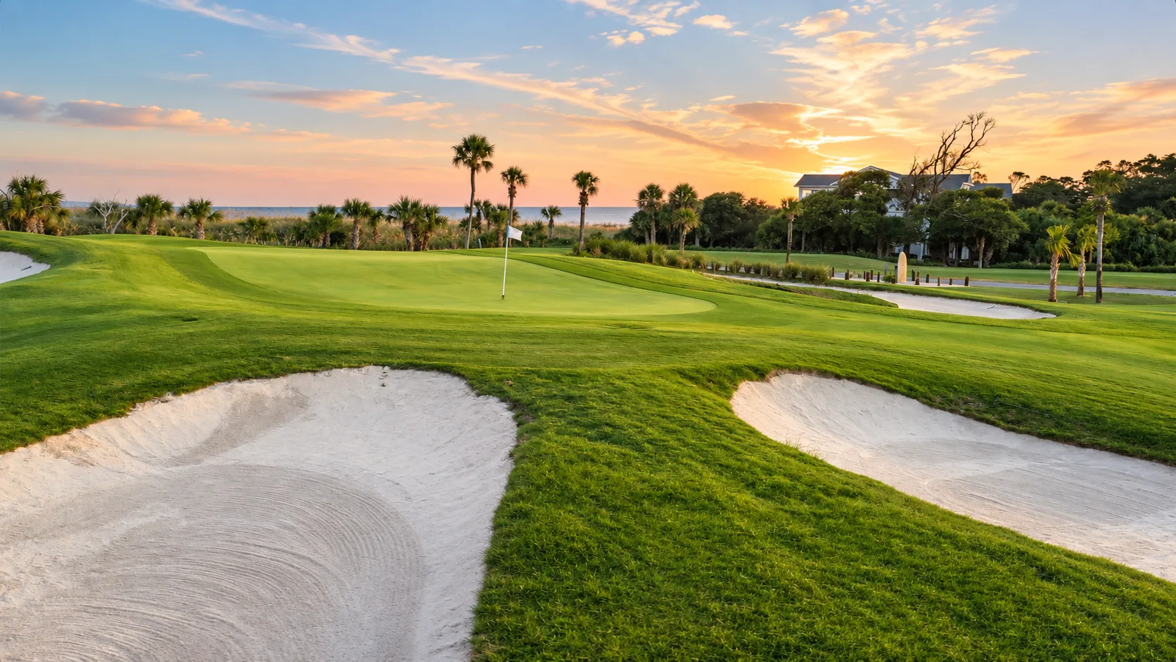 Bunkers in front of a green with the ocean behind at sunset